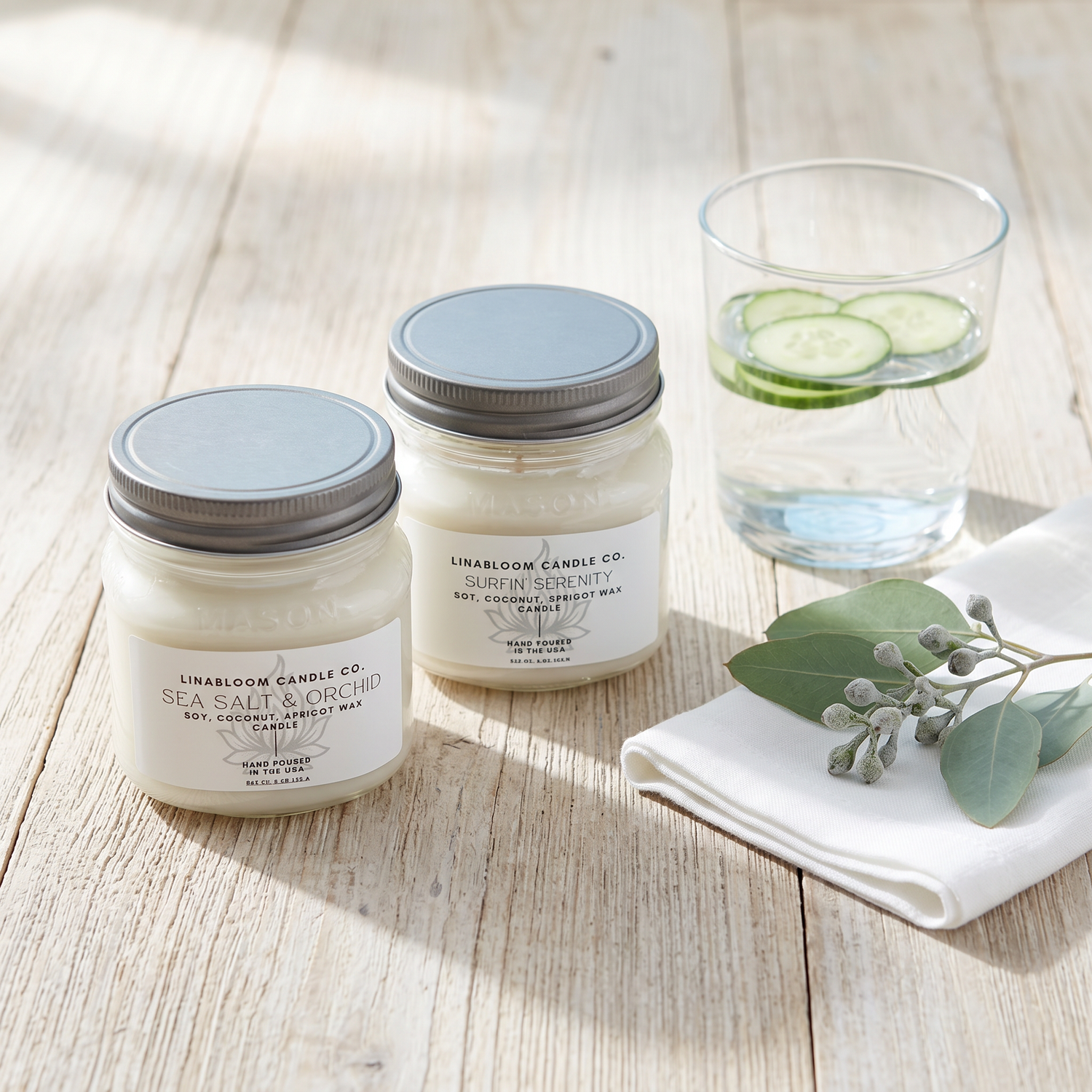 Fresh candle collection — Sea Salt & Orchid and Surfin' Serenity on sun-bleached wood with cucumber water and eucalyptus