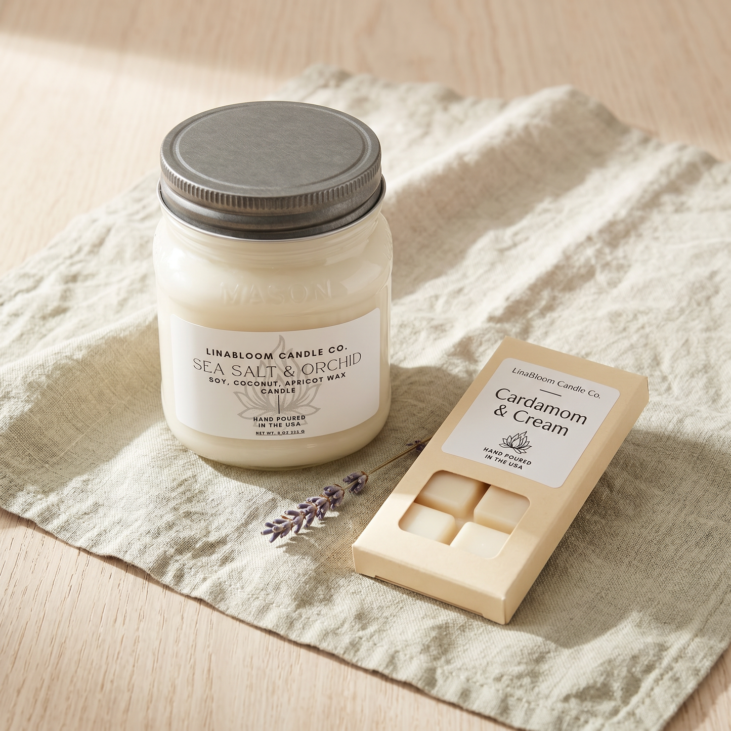 A LinaBloom 12oz Sea Salt & Orchid mason jar candle beside a 1.5oz Cardamom & Cream snap bar wax melt on linen