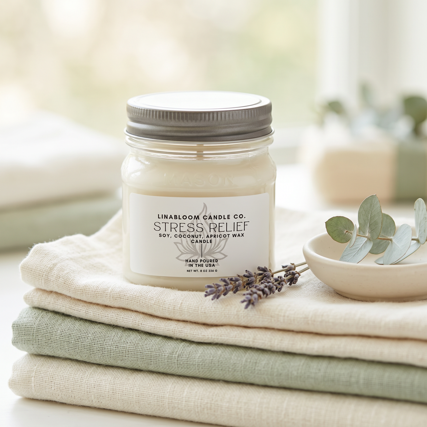 Stress Relief 8oz LinaBloom candle on folded sage and cream linen with dried lavender and eucalyptus