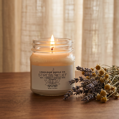 Stress Relief 8oz LinaBloom candle lit, with dried lavender and chamomile by a sunlit linen curtain