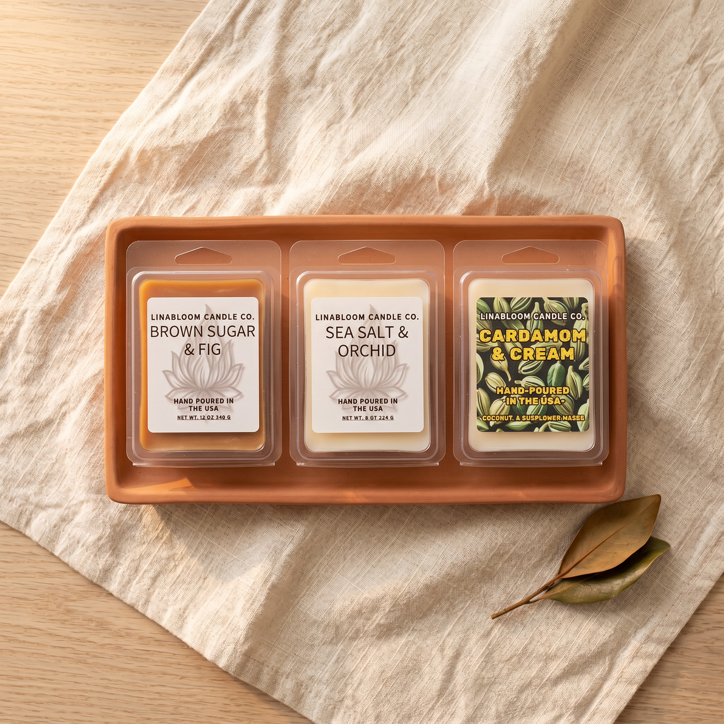 Three LinaBloom 2.6oz clamshell wax melts — Brown Sugar & Fig, Sea Salt & Orchid, Cardamom & Cream — on a terracotta tray