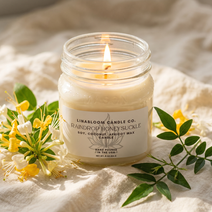 Raindrop Honeysuckle 8oz LinaBloom candle lit, with honeysuckle blossoms and jasmine on soft cream linen