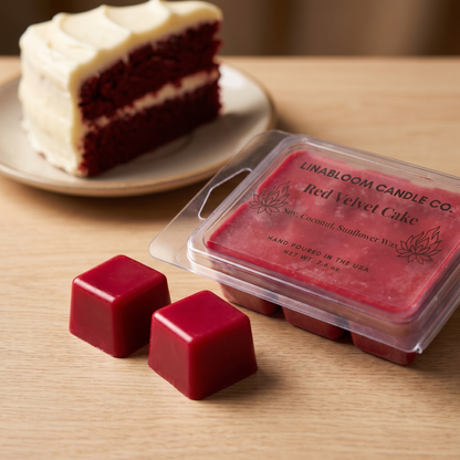 Red Velvet Cake LinaBloom wax melt — two deep red wax cubes beside the open clamshell and a slice of red velvet cake on pale oak