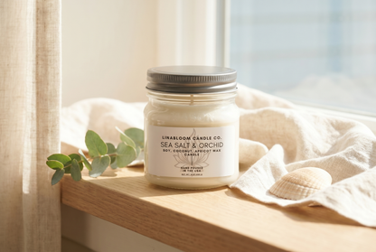 Lina Bloom Sea Salt & Orchid candle on a sunlit windowsill with linen and eucalyptus