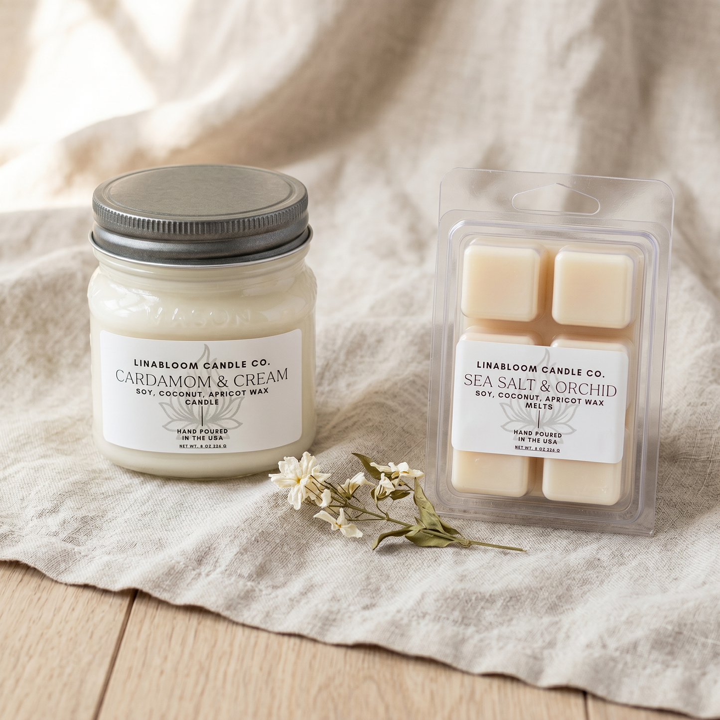 A LinaBloom 8oz Cardamom & Cream candle and 2.6oz Sea Salt & Orchid clamshell wax melt on linen